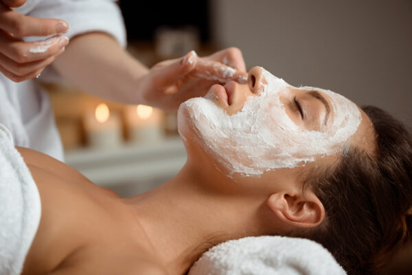 Young beautiful girl in mask for face relaxing in spa salon. Personalized Facials