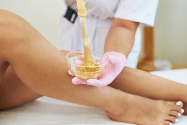 Cosmetologist is doing depilation. The procedures at the beautician Waxing